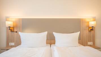 A double bed with white linens, two bedside lamps, and a wooden headboard.