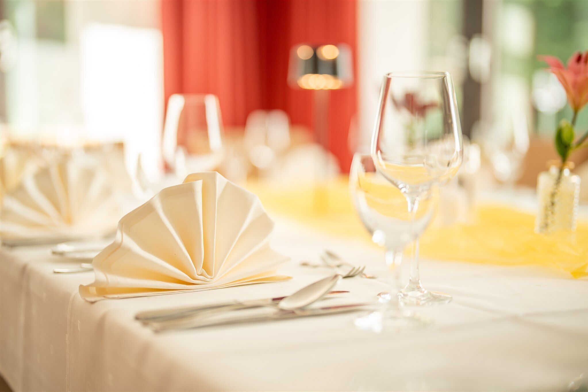 Una mesa dispuesta con manteles blancos, servilletas dobladas y copas de vino.