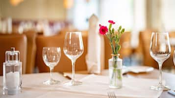 A dining table set with wine glasses, a salt shaker, and a vase with flowers.