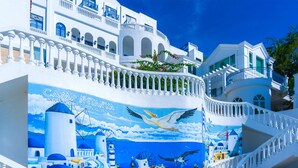 Un edificio blanco con un mural de una escena costera y un letrero que dice 'Camp Santorini of Manila, Batangas'.