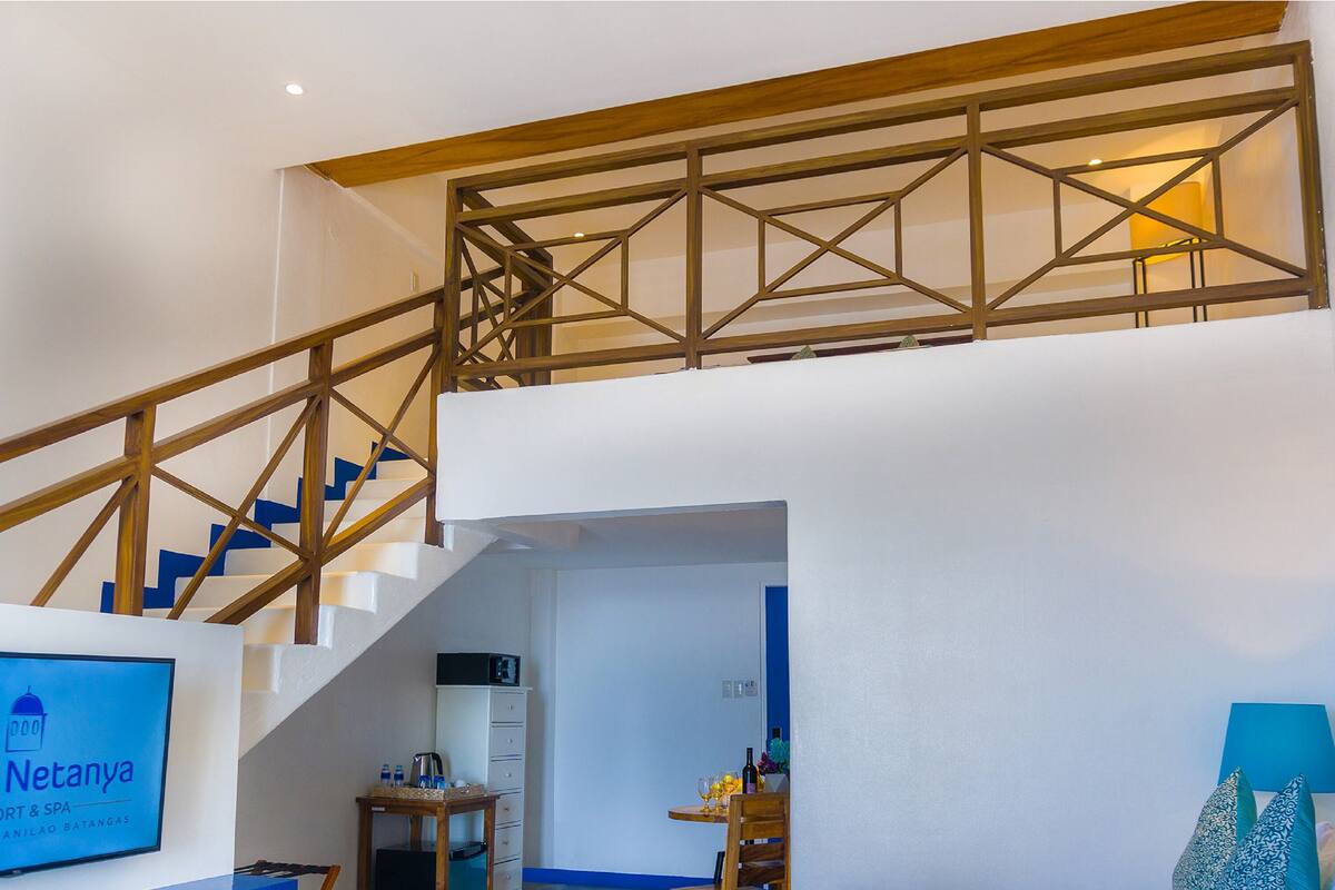 Interior de hotel con una escalera, un escritorio, una cama y un letrero que dice Camp Netanya.