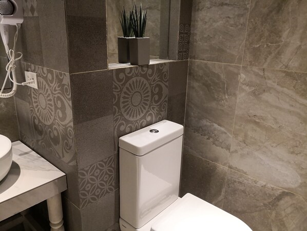 A bathroom with a toilet, a sink, and a hairdryer on a wall.