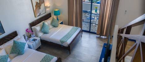 A hotel room with two beds, a balcony with a view, and a painting on the wall.