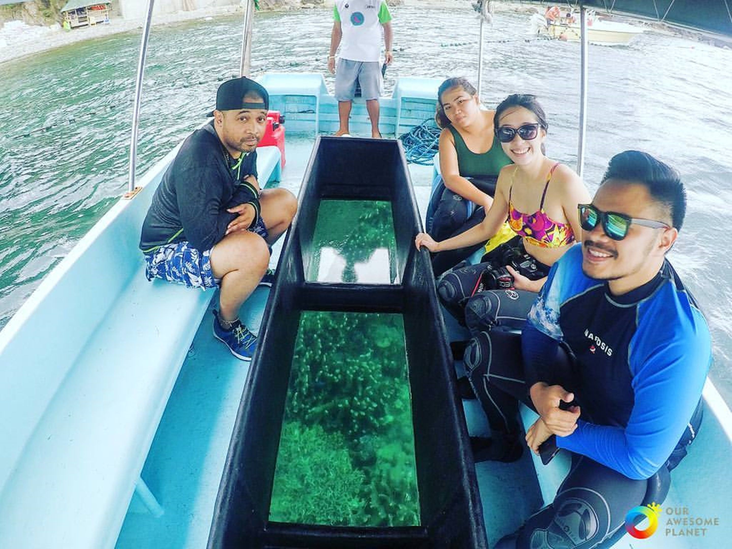 A boat with four people seated, a person standing at the back, and a clear view of the water through a window.