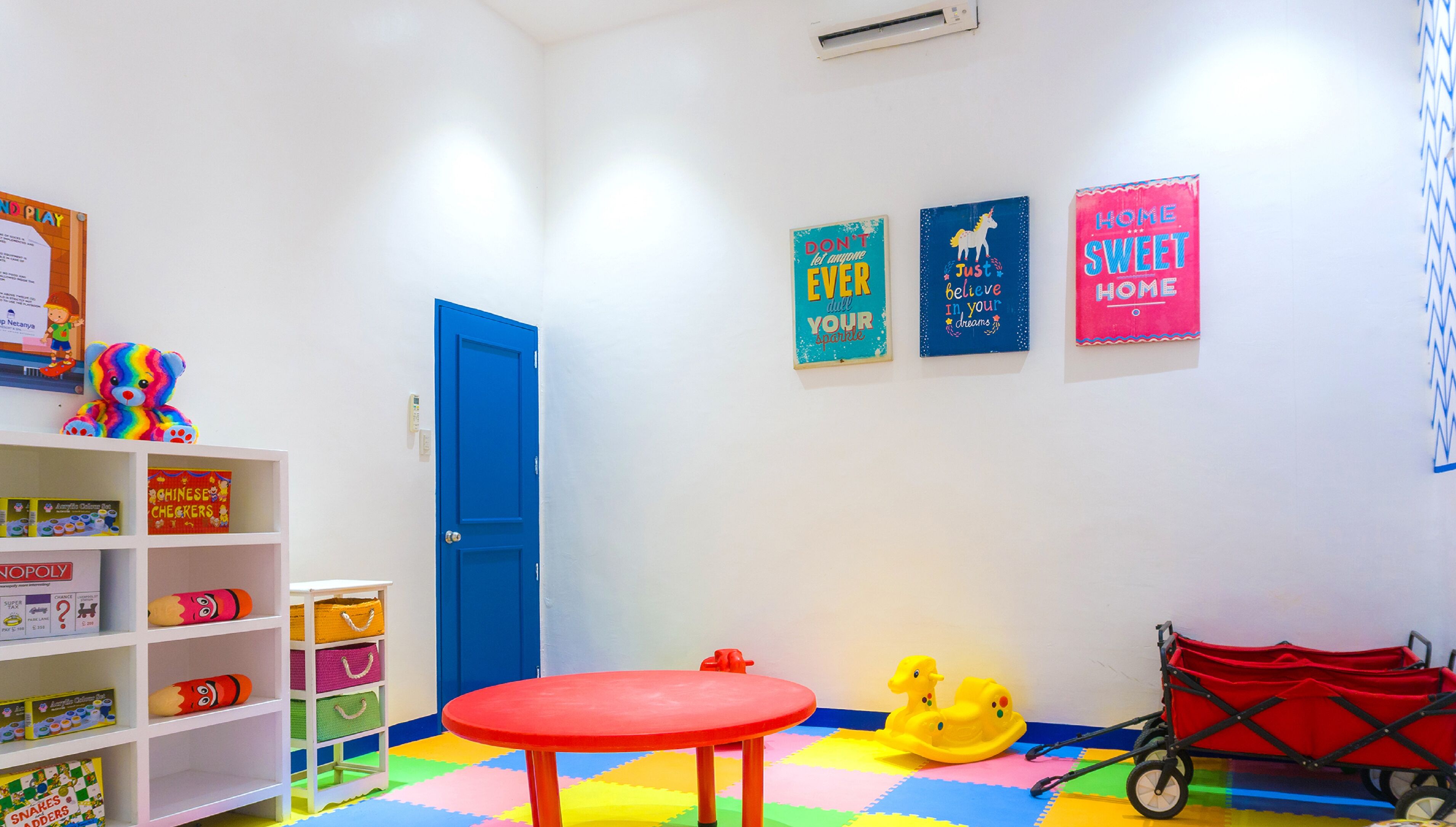 A brightly colored children's playroom with a red table, colorful wall decorations, and various toys.