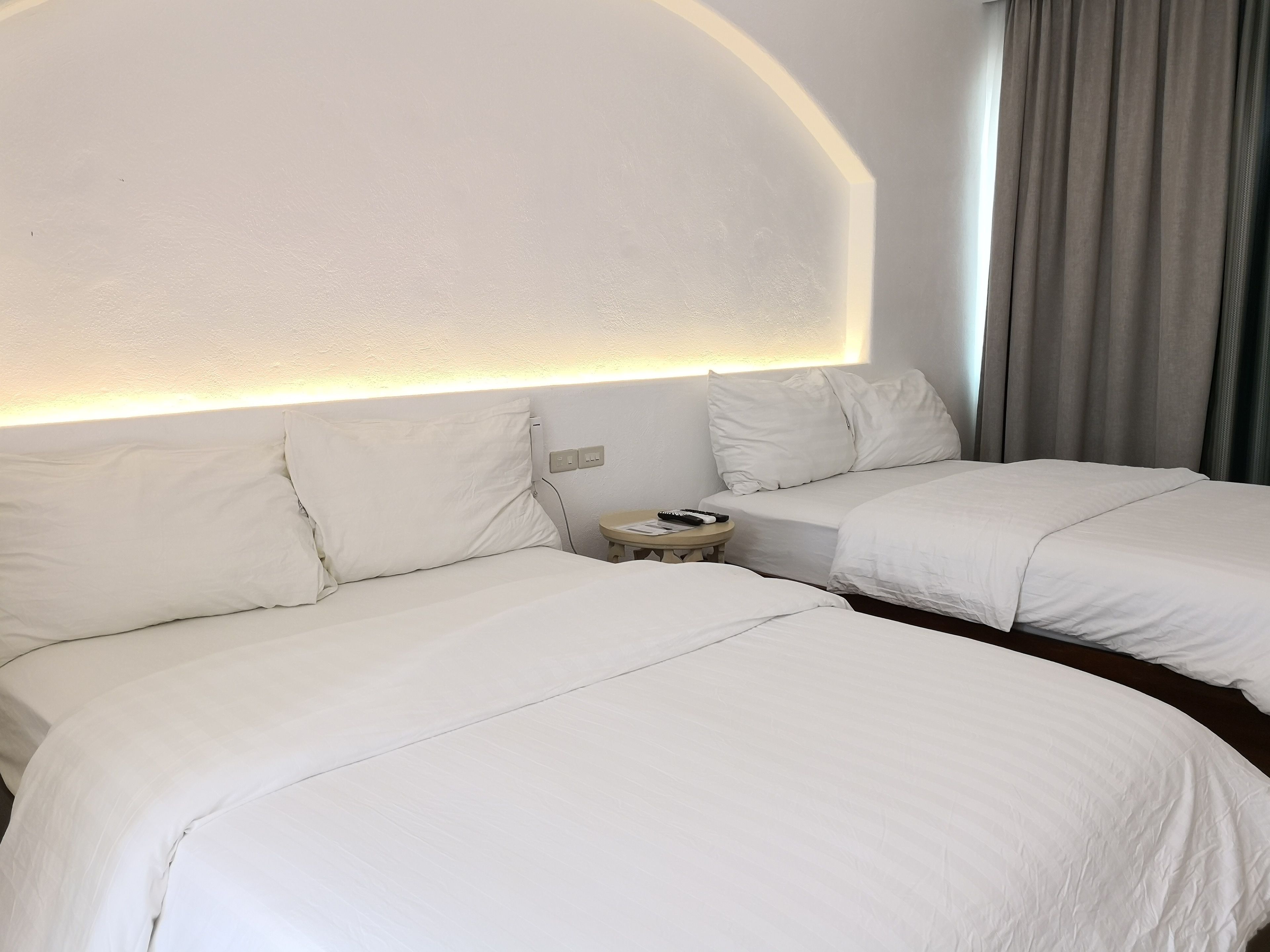 Ein Hotelzimmer mit zwei Betten, einem Nachttisch und einer Wandleuchte.