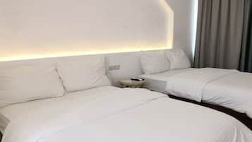 A hotel room with two beds, a bedside table, and a wall-mounted light.