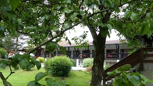 A courtyard with a tree, a small bush, and a building with a balcony. - Hotel restaurant la vieille ferme (Etupes)
