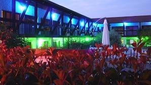 A building with a modern architectural design, featuring a prominent blue and green color scheme. - Hotel restaurant la vieille ferme (Etupes)