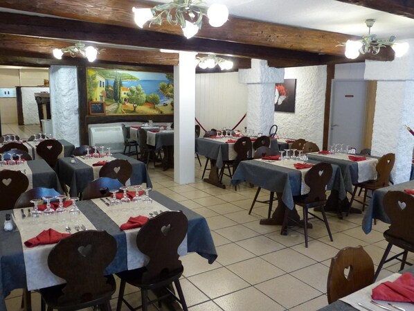 Un restaurante con varias mesas dispuestas para comer, sillas con forma de corazón y un mural en la pared.