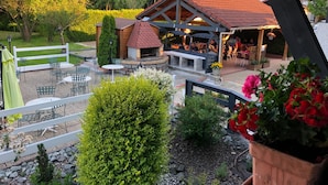 An outdoor patio area with a barbecue, seating, and a view of the surrounding greenery. - Hotel restaurant la vieille ferme (Etupes)