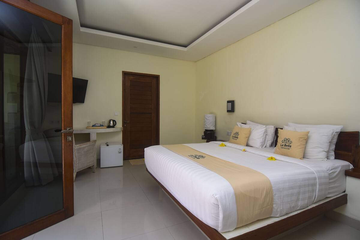 Ein Hotelzimmer mit Bett, Fernseher, Kaffeeautomat und Tür.