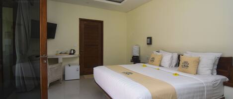 A hotel room with a bed, a television, a coffee machine, and a door.