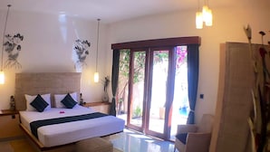 A spacious bedroom with a large bed, a sitting area with a chair, and a sliding glass door leading to an outdoor area. - La Bella - Hotel Villa & Spa (Gili Trawangan)