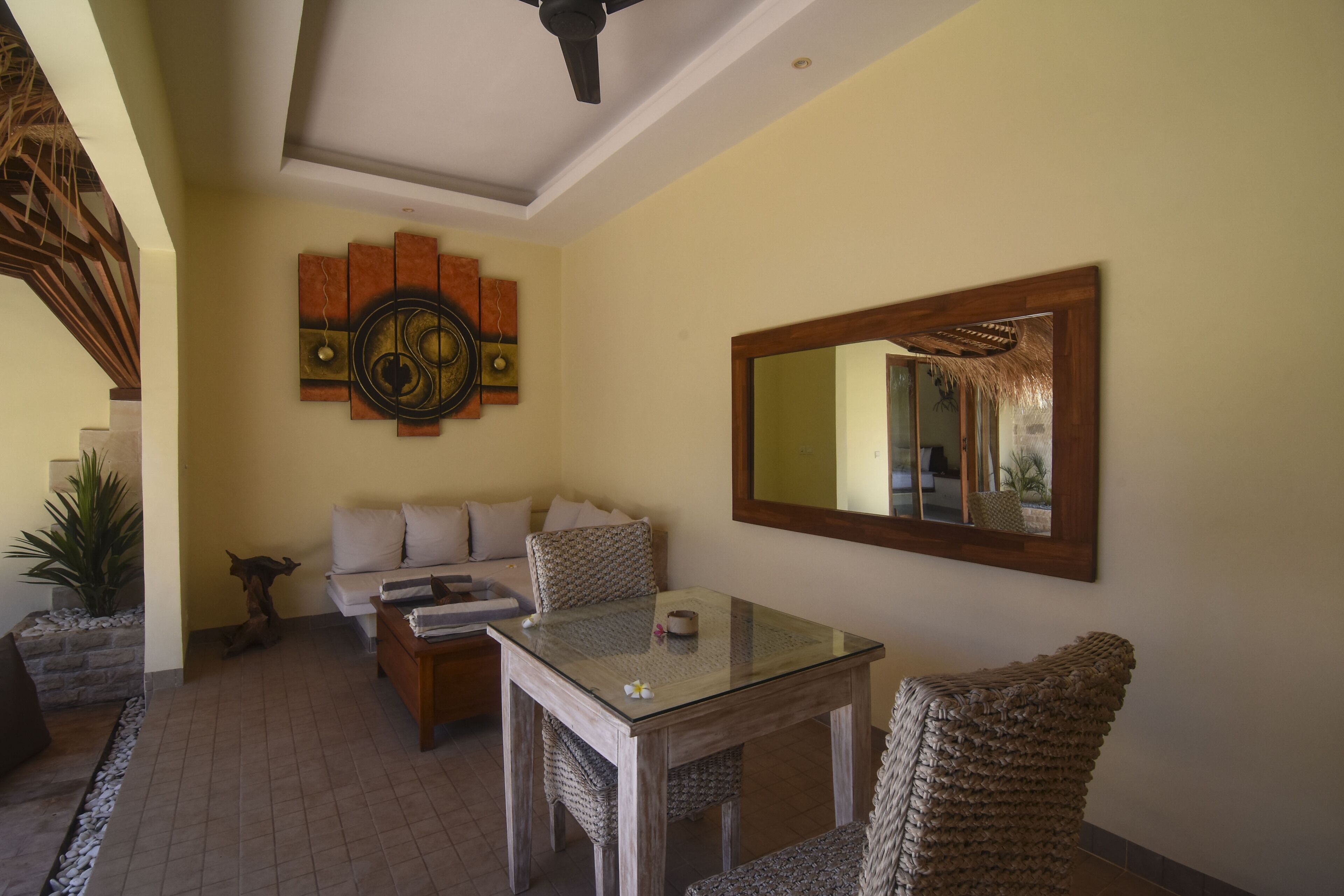 Una sala de estar con un sofá, una mesa con cubierta de vidrio y un espejo grande en la pared.