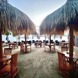 Di pantai, pasir putih, kursi berjemur, dan payung pantai