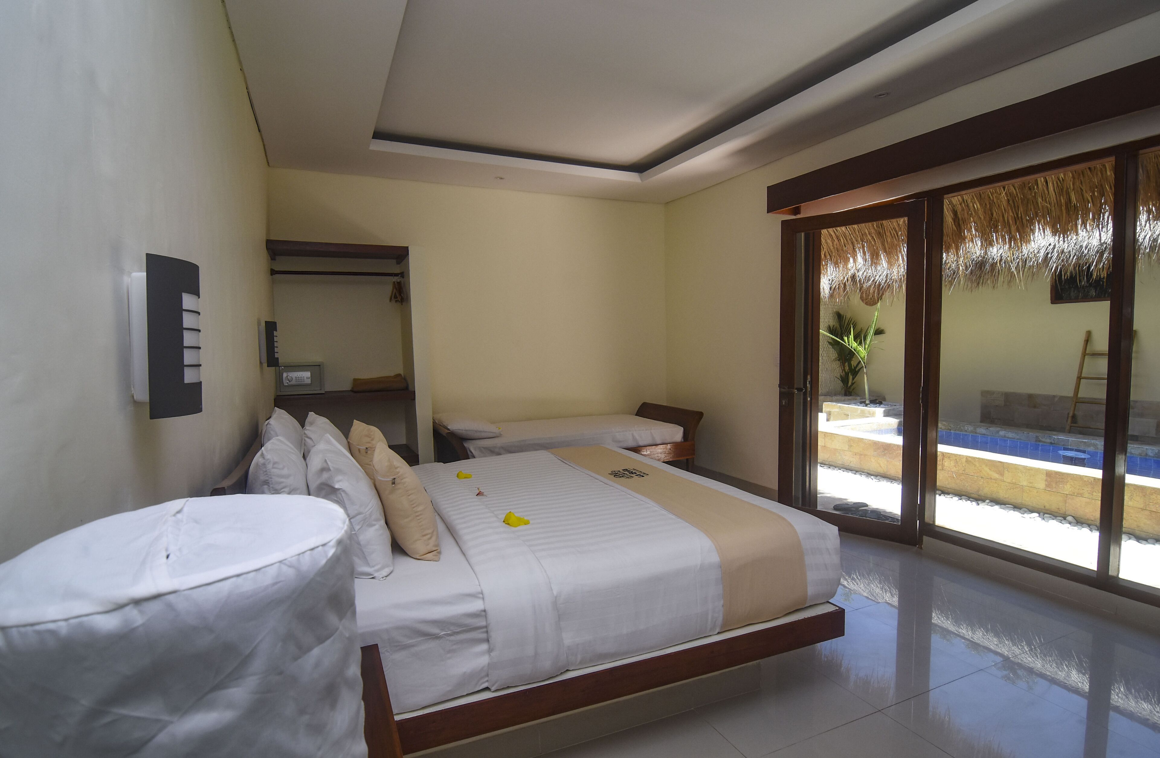 A hotel room with two beds, a bathroom, and a large sliding glass door leading to a pool area.