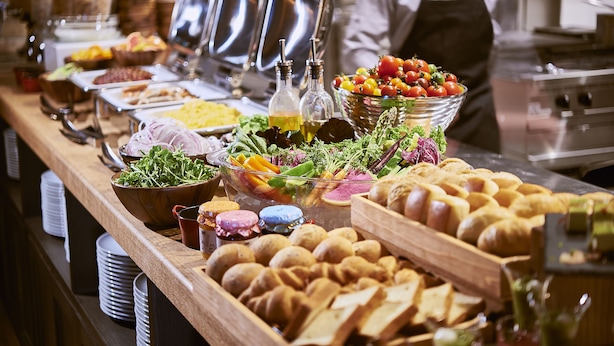 Un buffet proposant une variété de plats, notamment des salades, des fruits et du pain.
