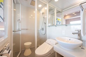 A modern bathroom with a glass shower enclosure, a white toilet, and a large vessel sink.