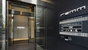 Une entrée moderne avec une porte en verre, une enseigne indiquant le nom « FEMM » et l’adresse « 4F, bâtiment principal de l’hôtel Leum Taikyo ».