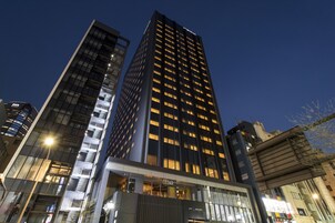 A high-rise building with multiple floors and a glass facade, featuring a prominent 'CEDAR' sign at the entrance.