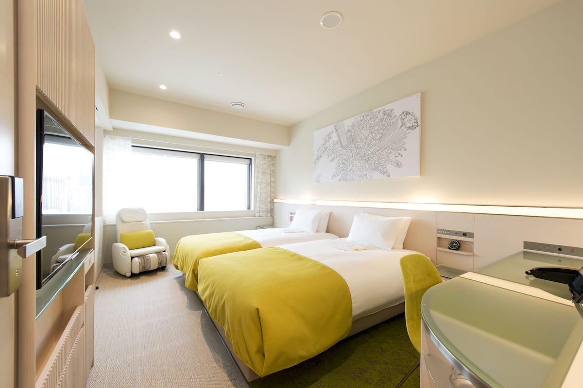 Habitación de hotel con dos camas, un sofá, un escritorio y una ventana.