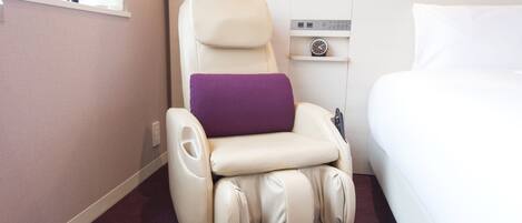 Una silla de masaje con panel de control, una cama y un ventanal.