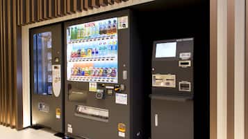 A vending machine with a variety of drinks and snacks, a money exchange machine, and a coin outlet.