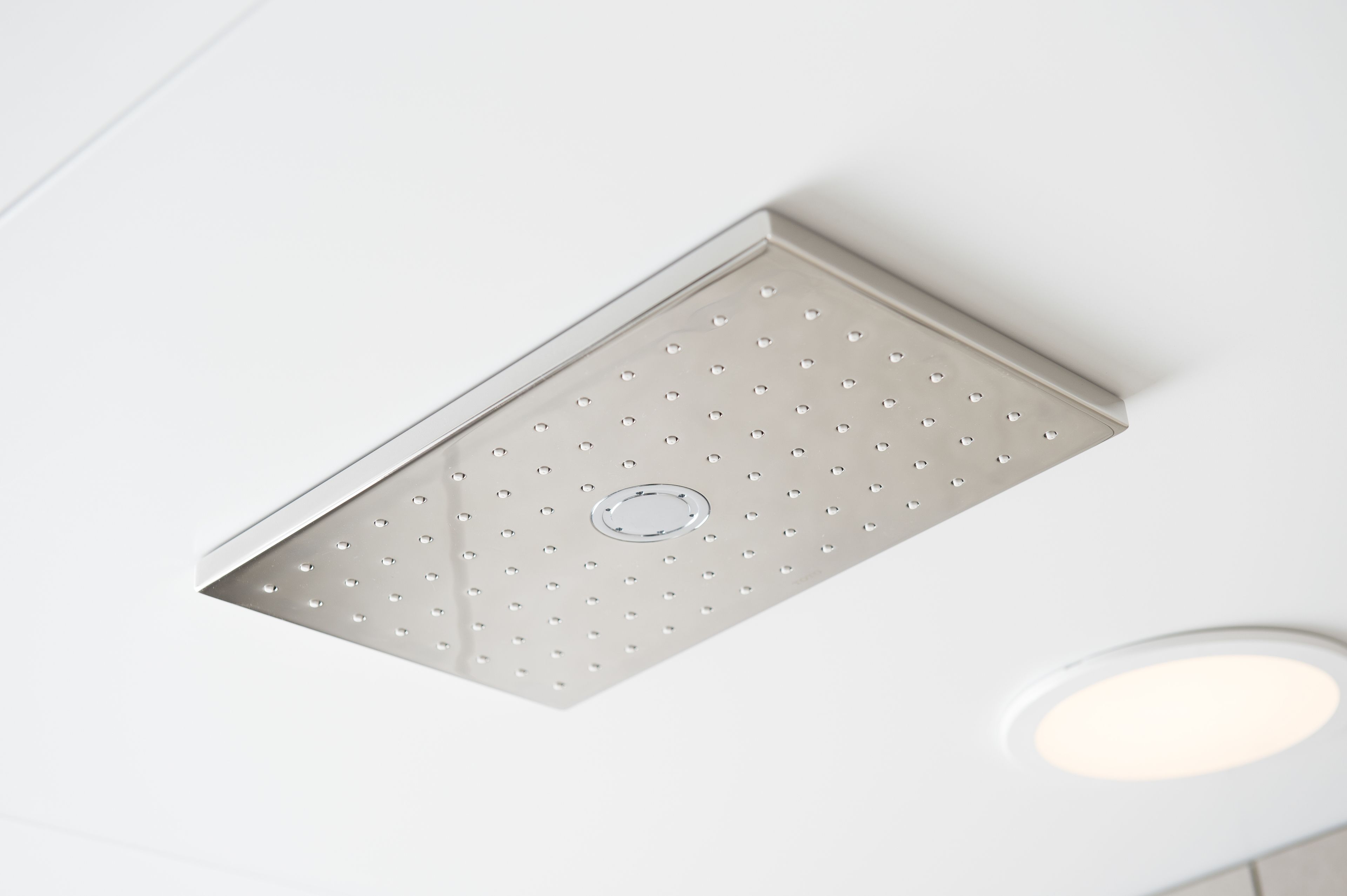 A ceiling with a recessed light fixture and a ventilation grille.