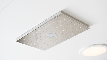 A ceiling with a recessed light fixture and a ventilation grille.