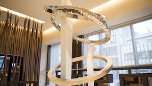 Un intérieur moderne agrémenté d’une sculpture métallique en forme de spirale, d’un distributeur automatique et d’un espace détente avec des bancs.