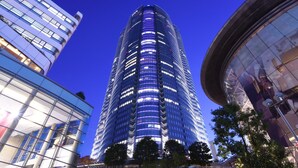 Un immeuble moderne de grande hauteur, doté d’une façade incurvée, entouré d’autres constructions contemporaines.