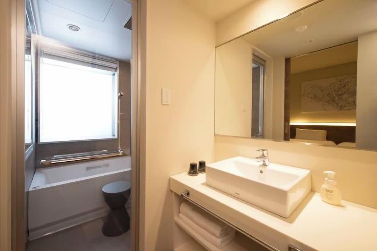 A modern bathroom with a large mirror, a sink, and a toilet.