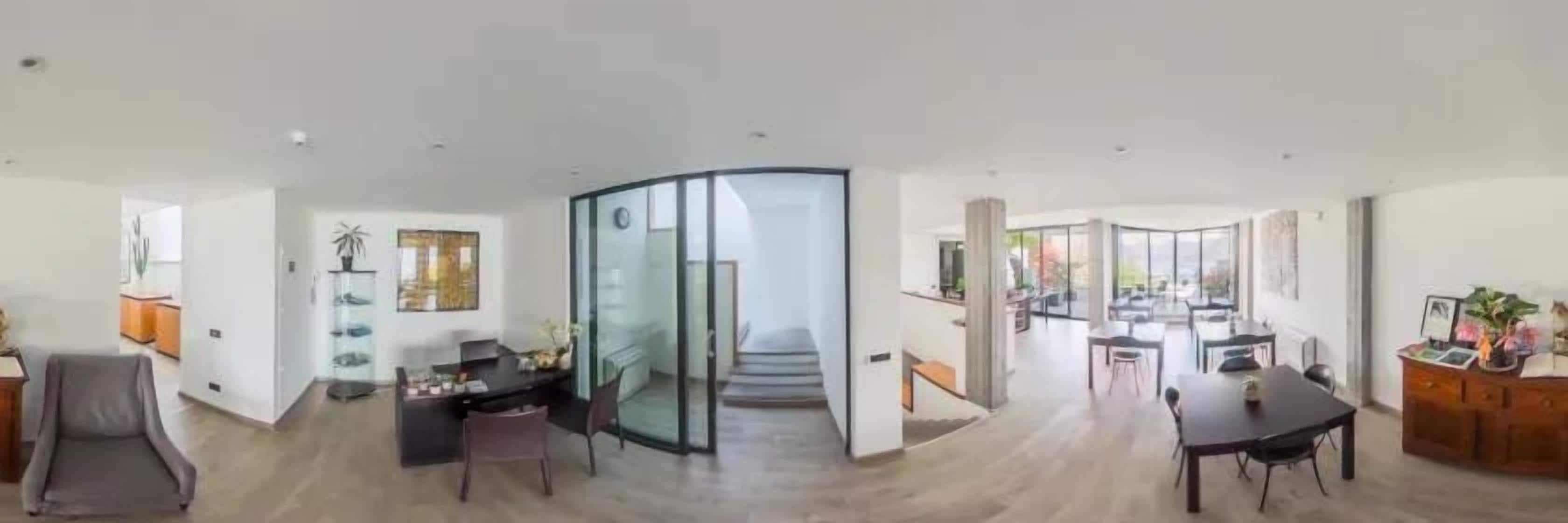 A spacious living area with a dining table, seating, and a glass partition.