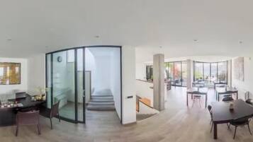 A spacious living area with a dining table, seating, and a glass partition.
