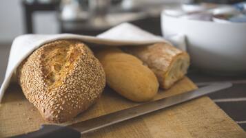 Une miche de pain sur une planche à découper en bois, avec un couteau.