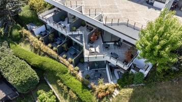 Un edificio moderno de varios pisos con zonas de estar al aire libre y una terraza en la azotea.