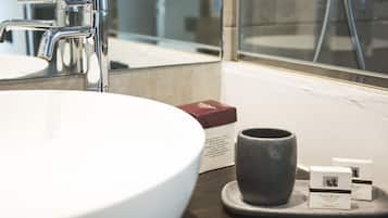 A bathroom with a white sink, chrome faucet, and a mirror. There are two boxes of soap and a ceramic mug on the counter.
