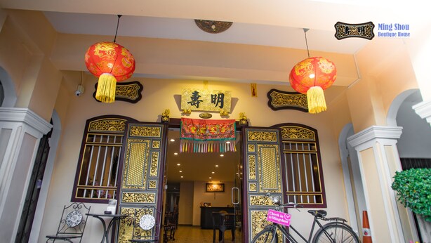 A traditional Chinese gate with intricate designs and a red lantern hanging above. - Ming Shou Boutique House (Phuket)