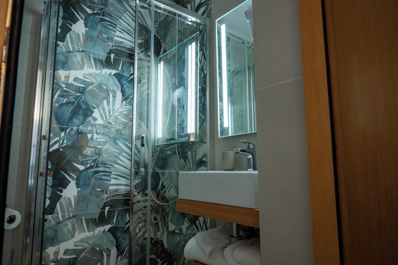 Une salle de bain avec une douche à parois de verre, un lavabo et un miroir.