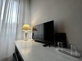 Een moderne hotelkamer met een flatscreen televisie, een bedlamp, een dienblad met glazen en een krijtbordmenu.
