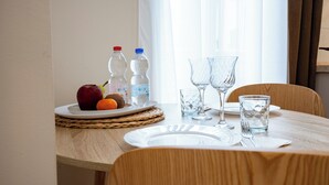 A dining table with a plate of fruit, two water bottles, and two empty glasses. - Hotel Genova Liberty (Genoa)