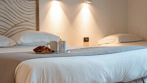 A hotel room with a bed, two wall-mounted lights, a bedside table with a cup and a croissant, and a headboard with a leaf pattern. - Hotel Genova Liberty (Genoa)