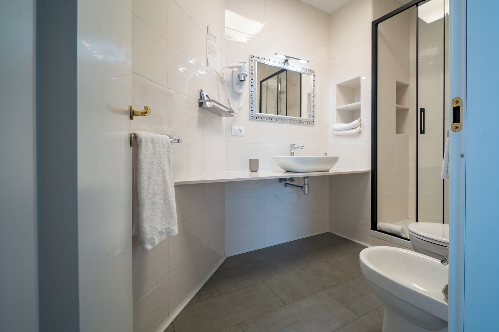 A bathroom with a white sink, a mirror, a glass shower enclosure, and a toilet.