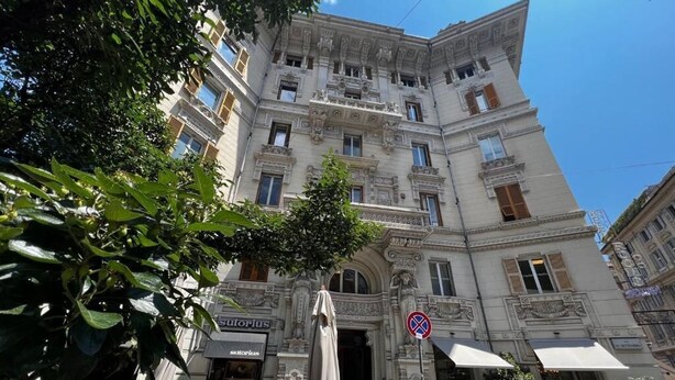 A historic building with ornate architecture, outdoor seating, and a no parking sign. - Hotel Genova Liberty (Genoa)