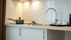 A kitchen with a sink, a green pot, a kettle, and a tray with cups. - Hotel Genova Liberty (Genoa)