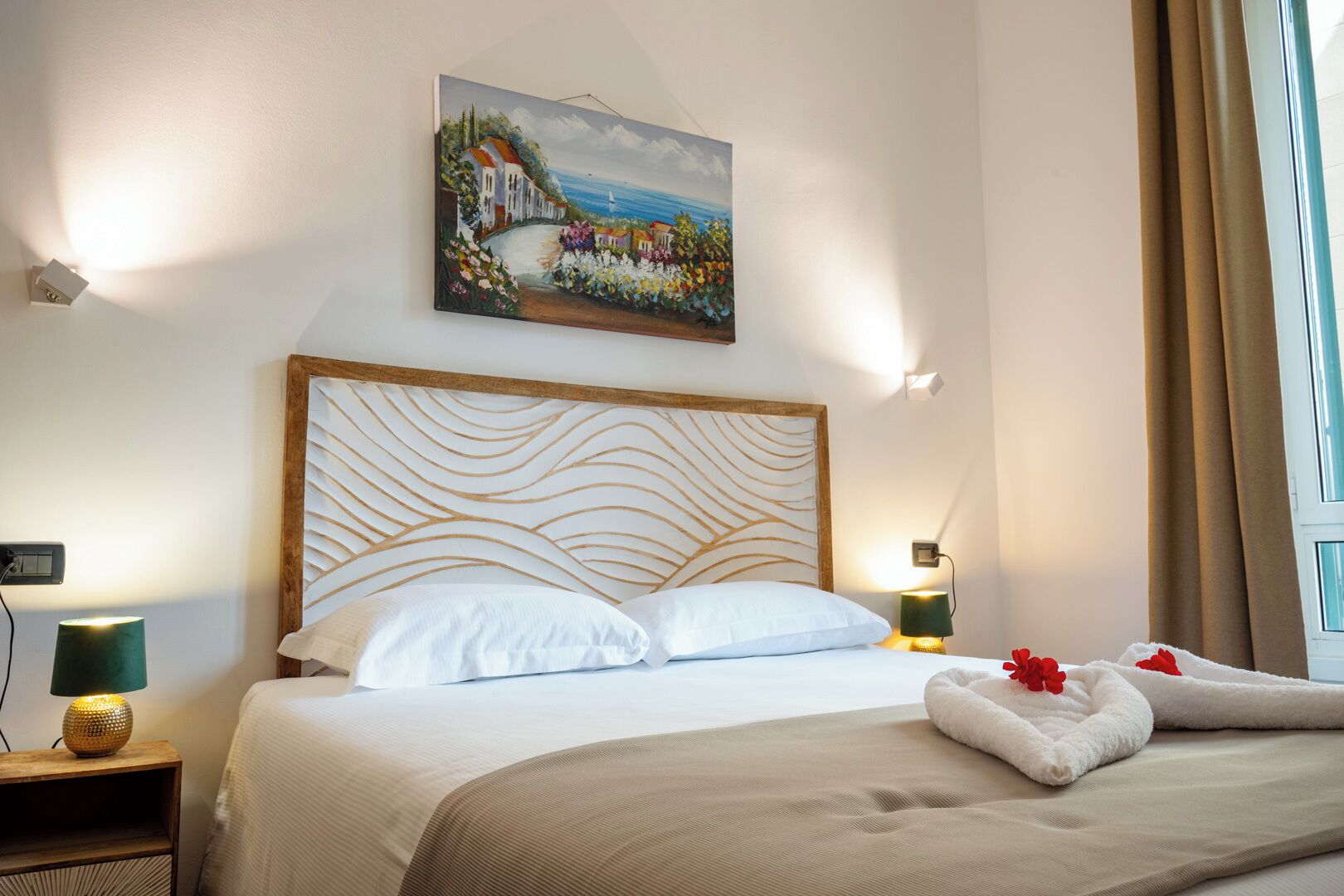 Una camera d'albergo con un letto, un quadro, un comodino e una lampada.