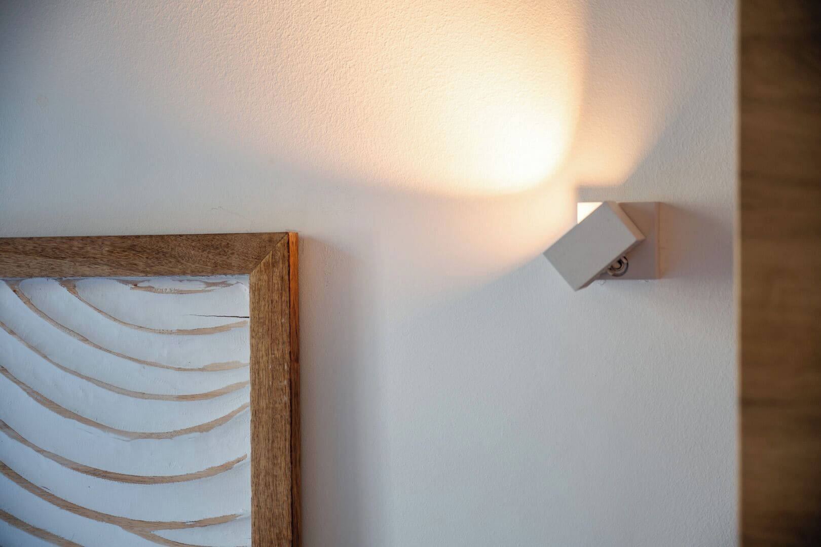 A wall-mounted light fixture next to a framed artwork.