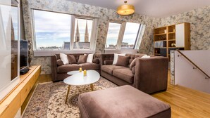 Een moderne woonkamer met een bruine hoekbank, een witte salontafel en uitzicht op een kathedraal door grote ramen.