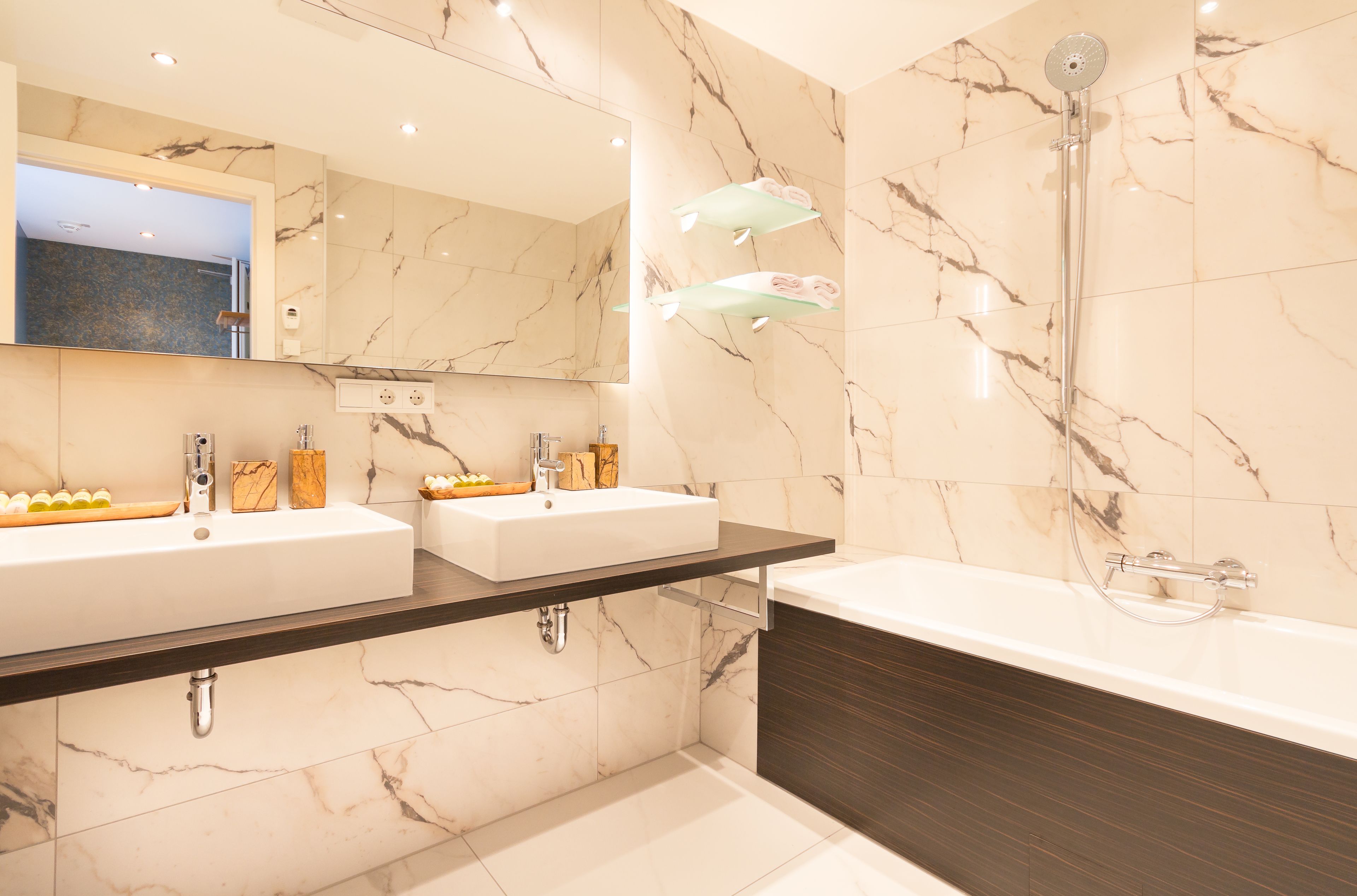 Un bagno moderno con due lavandini, uno specchio grande e una vasca da bagno.